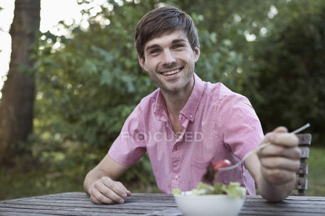 Мужчина ест за столом на открытом воздухе, вне городской сцены — стоковое фото