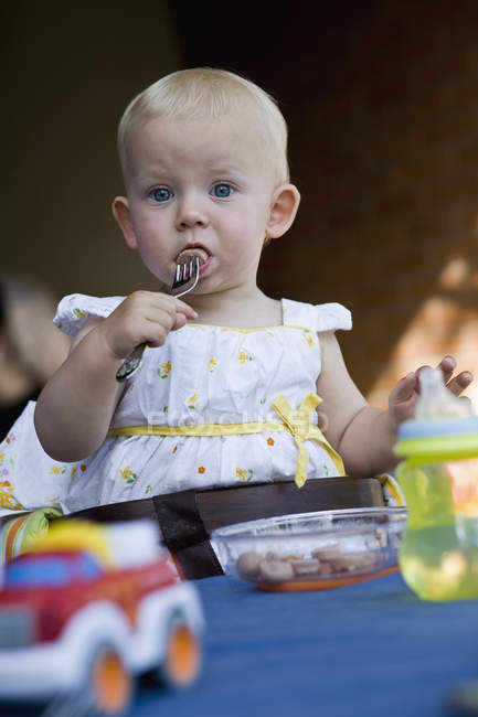 Un bambino che mangia fette di hot dog con una forchetta — Foto stock