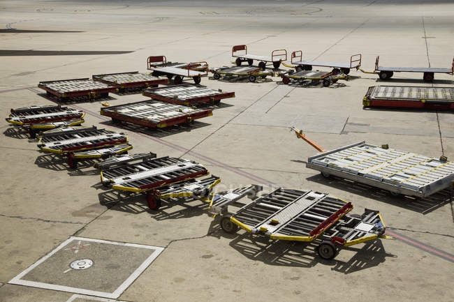 Vista de ángulo alto de remolques de equipaje vacíos en asfalto del aeropuerto - foto de stock