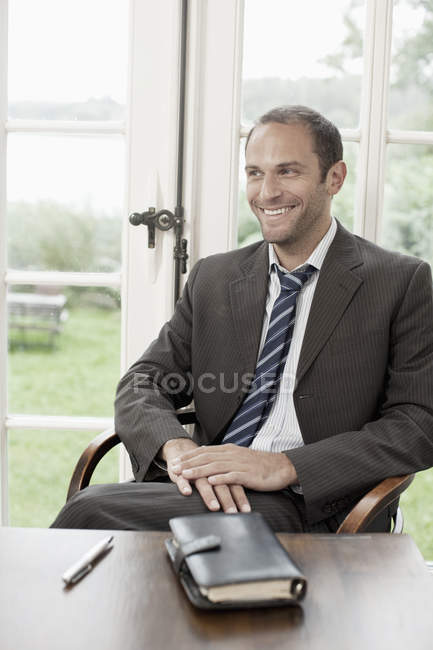 Portrait of a businessman sitting at a table and looking away — Stock Photo