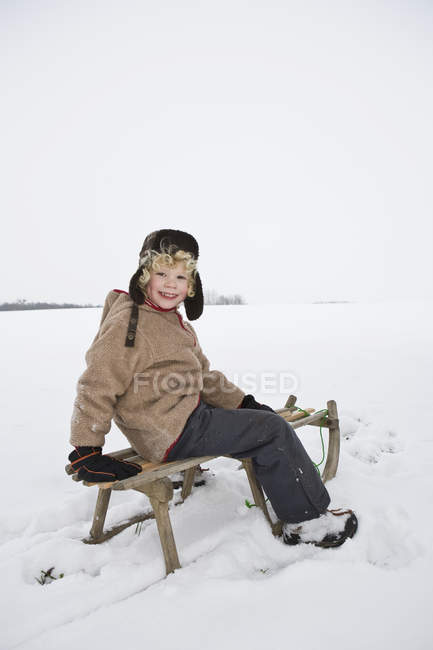 A boy sitting on a sled during daytime — Stock Photo