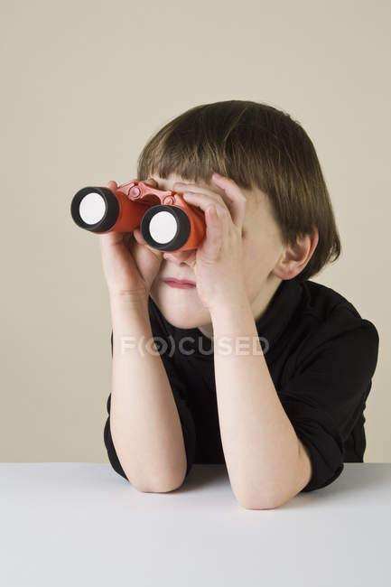 A boy using binoculars indoors — Stock Photo