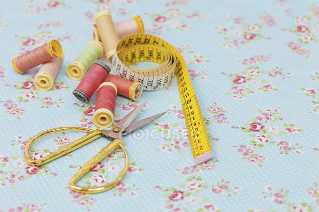 Still life of various spools and scissors with tape measure on blue fabric — Stock Photo
