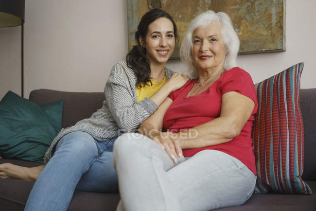 Portrait mère aînée souriante assise avec sa fille sur le canapé du salon — Photo de stock