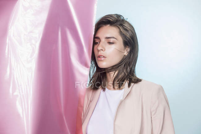 Retrato de una modelo de moda femenina posando con tela rosa y mirando hacia otro lado - foto de stock