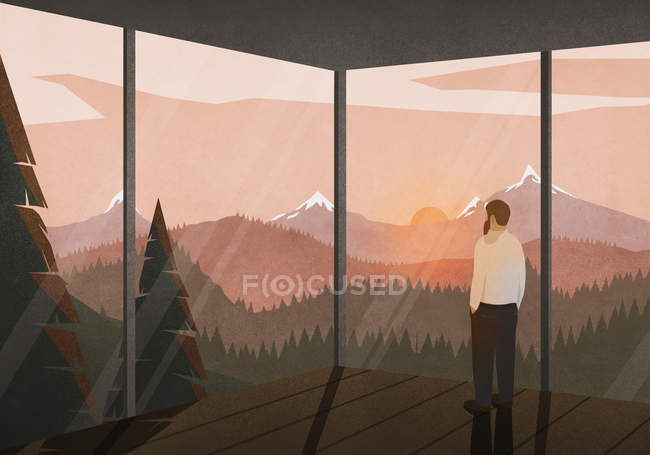 Человек наслаждается спокойным видом на закат за горами из стеклянного дома — стоковое фото