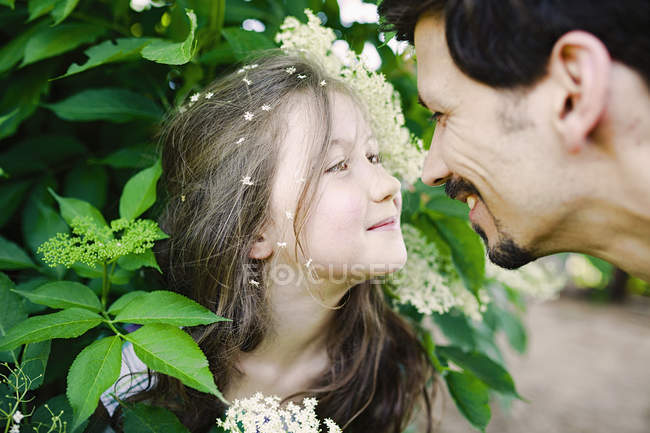 Affectionate father and daughter at flowering bush — Stock Photo
