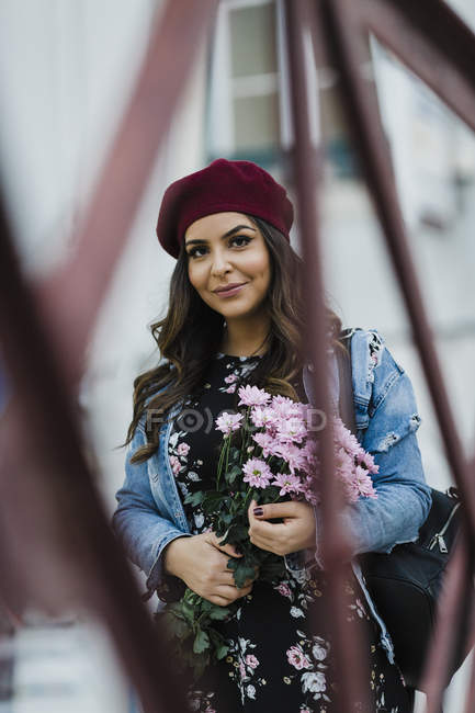 Retrato confiante de jovem mulher na boina segurando buquê de flores — Fotografia de Stock