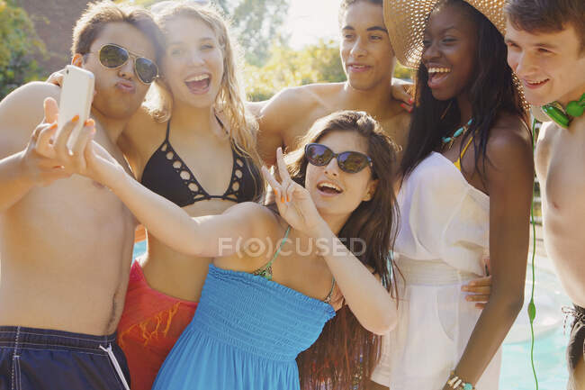 Happy teenage friends taking selfie with smarphone on sunny summer patio — стоковое фото