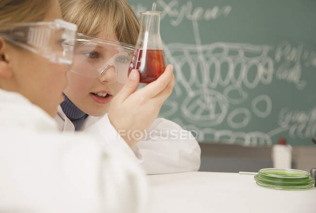 Старшеклассники изучают стакан жидкости в классе естественных наук — стоковое фото