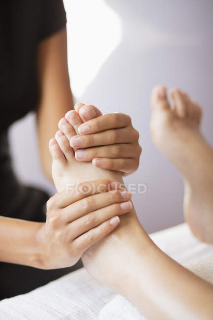 De cerca masajista femenina masajeando los pies del cliente - foto de stock