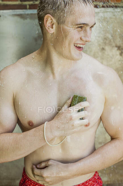 Felice giovane uomo con sapone doccia all'aperto — Foto stock