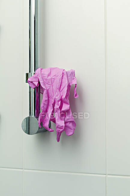 Pink protective gloves hanging on shower handle — Stock Photo