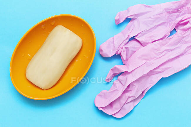 Мыло и розовые защитные перчатки на синем фоне — стоковое фото