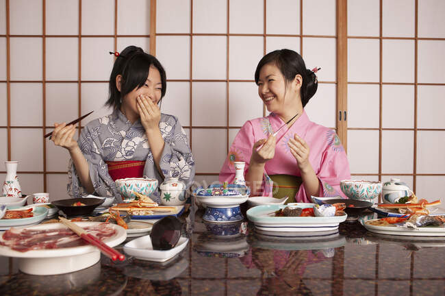 Счастливые молодые женщины в кимоно обедают в ресторане — стоковое фото