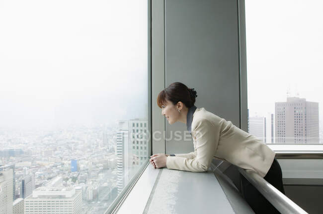 Donna d'affari guardando fuori alla vista della città da ufficio grattacielo — Foto stock