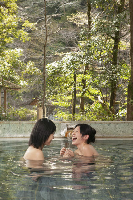Glückliche junge Freundinnen lachen im Pool in Onsen — Stockfoto