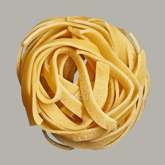 Close up uncooked pasta nest on gray background — Stock Photo