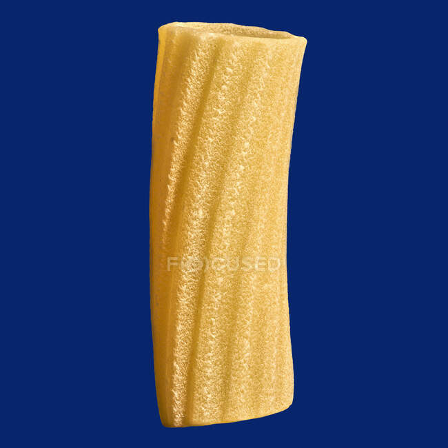 Close up uncooked penne rigate noodle on blue background — Stock Photo