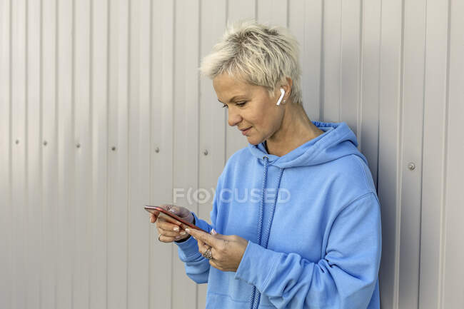 Woman with earbud headphones using smart phone — Stock Photo