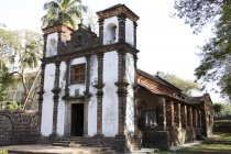 Seitenansicht der Kapelle der hl. Katherine, die tagsüber von Palmen über grünem Gras umgeben ist, Goa, Indien — Stockfoto