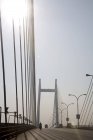 Vista da ponte moderna com fios e scooter em movimento na estrada perto de postes de lâmpada — Fotografia de Stock