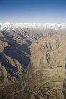 Veduta aerea delle montagne dell'Himalaya coperte di neve con case e campi lungo il fiume nella valle in primo piano come visto sul volo da Delhi a Leh-Ladakh. India — Foto stock