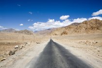 Narrow tar bituman road on the Leh-Kargil road stretch in the stren cold dsert landscape of Ladakh. Inde — Photo de stock