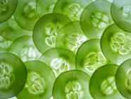 Скибочки огірків напівпрозора, зелена овочева кладка на білій поверхні — стокове фото