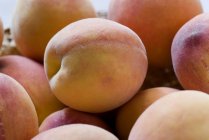 Wenige Pfirsiche Früchte im Korb über weißem verschwommenem Hintergrund — Stockfoto