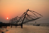 View of sunset at sandy beach with nets on construction against water,Ernakulam District, Kerala, India. — Stock Photo