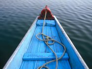 Вид на голубую деревянную лодку над спокойной речной водой и веревкой внутри — стоковое фото