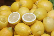 Лимоны целые и нарезанные, лежащие на белой тарелке — стоковое фото