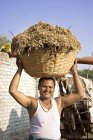 Un granjero indio sosteniendo comida de toros en su cabeza. Salunkwadi, Ambajogai, Beed, Maharashtra, India - foto de stock