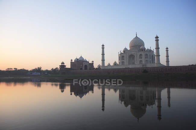 Vista lateral de Taj Mahal contra a água da lagoa com reflexão durante o dia — Fotografia de Stock