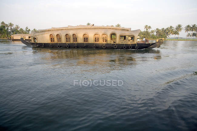 Vessel moving over water of river agaisnt trees on shore — Stock Photo