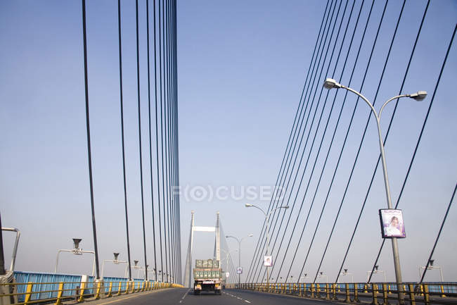 Вид на современный мост с грузовиком на дороге с фонарными столбами в дневное время — стоковое фото