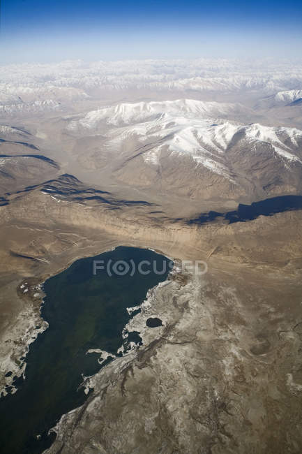Luftaufnahme des schneebedeckten Himalaya-Gebirges mit einem See im Vordergrund, wie auf dem Flug von delhi nach leh-ladakh zu sehen. Indien — Stockfoto