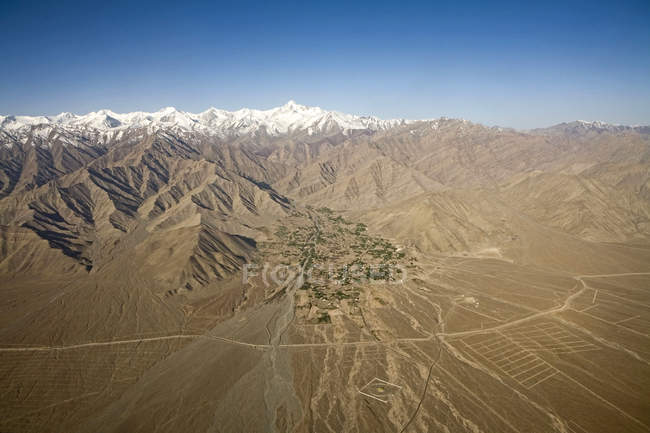 Veduta aerea delle montagne innevate dell'Himalaya con case e campi lungo il fiume nella valle vicino a Leh, come visto sul volo da Delhi a Leh-Ladakh. India — Foto stock