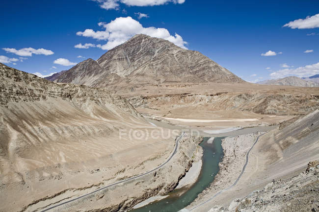 Confluence of green water of river Indus and muddy brown water of river Zanskar near Nimmu on the Leh-Kargil road with the barren Ladakh landscape in the background. Ladakh.India — Stock Photo