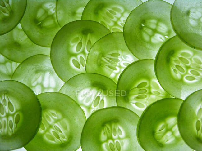 Огурец ломтики полупрозрачный, зеленый овощ укладки на белой поверхности — стоковое фото