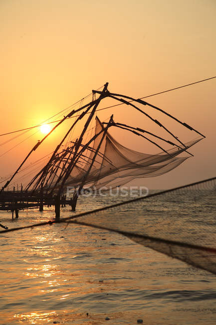 Vista del tramonto sulla spiaggia sabbiosa con reti in costruzione contro l'acqua, distretto di Ernakulam, Kerala, India . — Foto stock