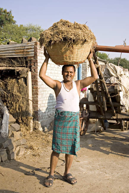 Un contadino indiano che tiene del cibo per tori in testa. Salunkwadi, Ambajogai, Beed, Maharashtra, India — Foto stock
