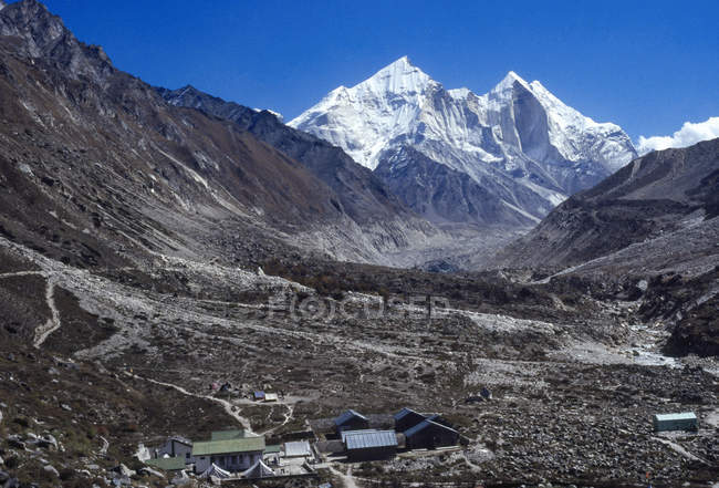 Vista delle cime delle montagne e campo a piedi con pietre durante il giorno — Foto stock