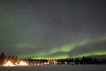 Aurora boreal e Via Láctea sobre a aldeia — Fotografia de Stock