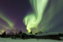Aurora boreal sobre cabines de madeira — Fotografia de Stock