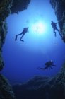 Saída de caverna com três mergulhadores, Grotta dei Cirri, Ustica, Itália — Fotografia de Stock