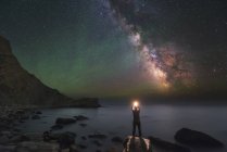 Homem de pé na costa do Mar Negro à noite sob Via Láctea e brilho de ar verde — Fotografia de Stock