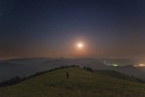 Mann steht nachts auf Bergen unter Mond, Sudak, Krim — Stockfoto