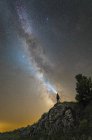 Man standing on rocks of Lago-Naki plateau and shining flashlight on Milky Way, Russia — Stock Photo